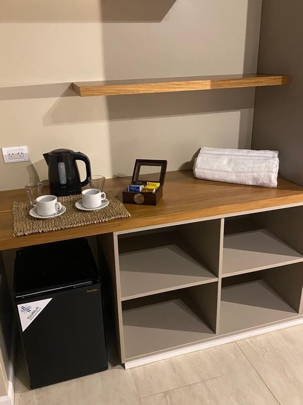 Kitchenette con cafetera y tazas sobre una mesa de madera