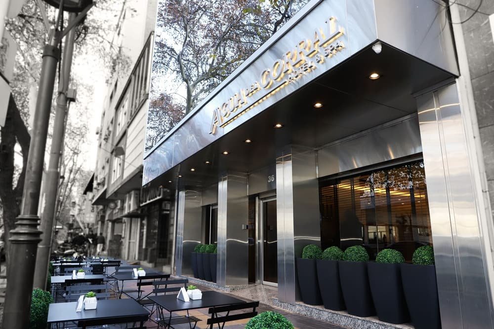 Zona de mesas y sillas al aire libre con la entrada del hotel