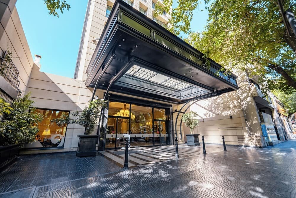 Entrada do hotel com marquise de vidro e calçada de ladrilhos