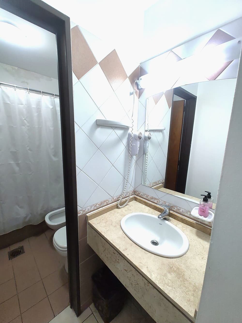 Baño con lavatorio blanco, espejo, ducha e inodoro