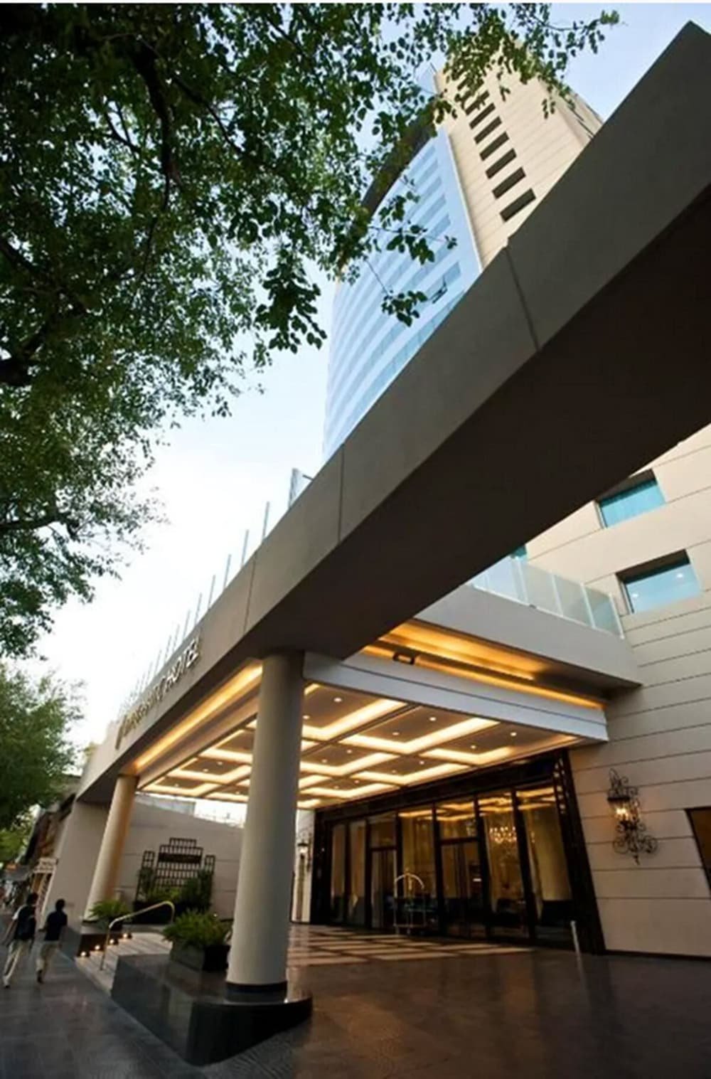 Modern hotel entrance with covered walkway, large columns and glass facade