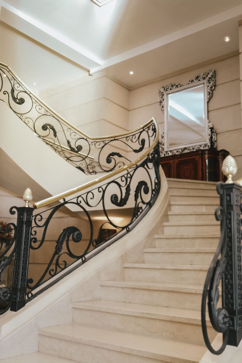 Marble staircase with ornate black metal railings and a decorative mirror
