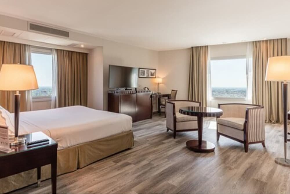 Hotel room with a bed, desk, chair, table and TV