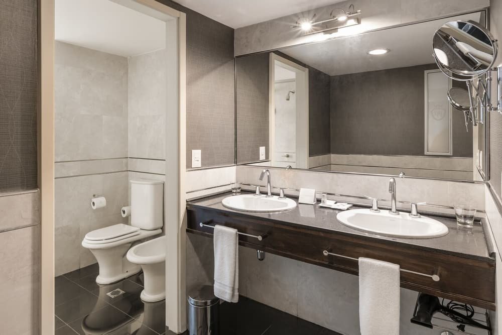 Modern bathroom with two sinks, a toilet and a large mirror