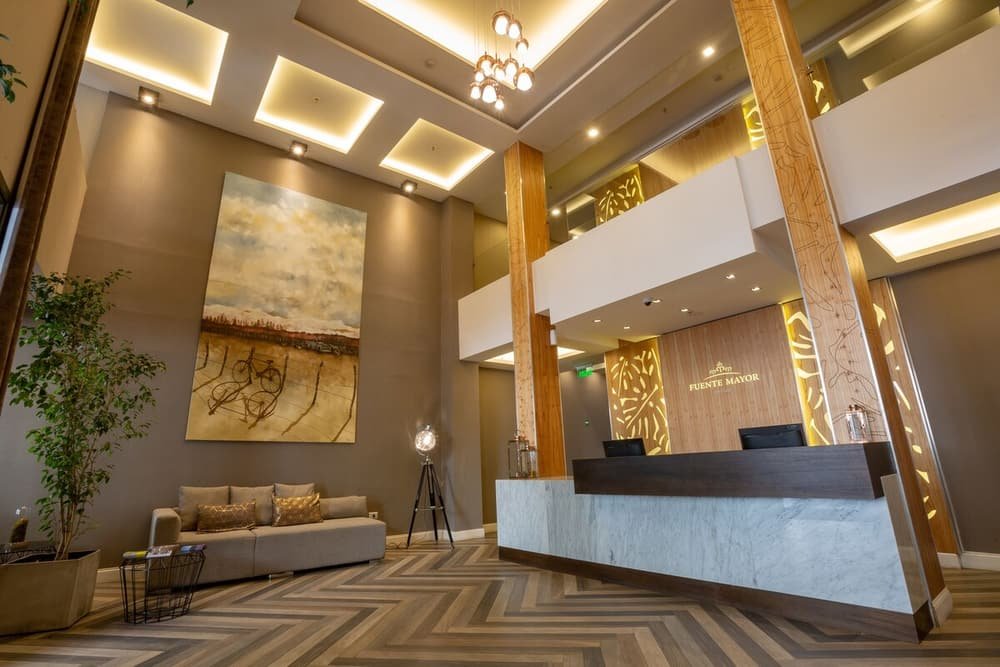 Hall moderno con mostrador de recepción, sofá, gran cuadro abstracto y planta