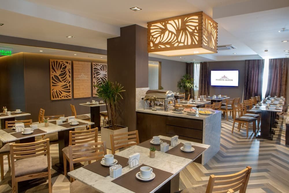 Comedor del hotel con varias mesas, sillas y sector de cocina