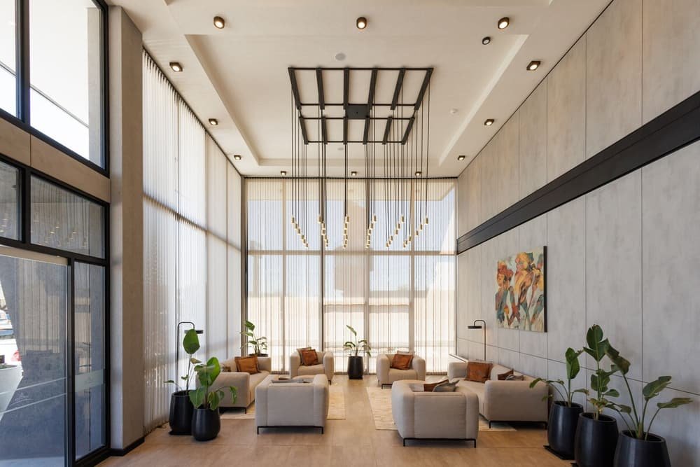 Lobby amplio con grandes ventanales, mobiliario moderno y techo de diseño original