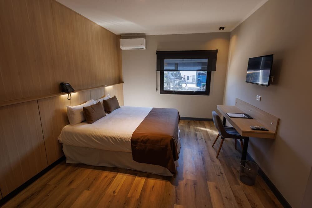 Quarto com cama, criado-mudo e escrivaninha junto à janela