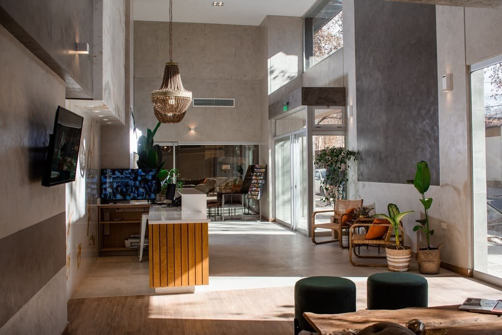 Lobby espaçoso com balcão de madeira, poltronas e grandes janelas