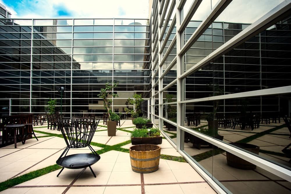 Edificio moderno de vidrio con sector exterior de sillas y plantas