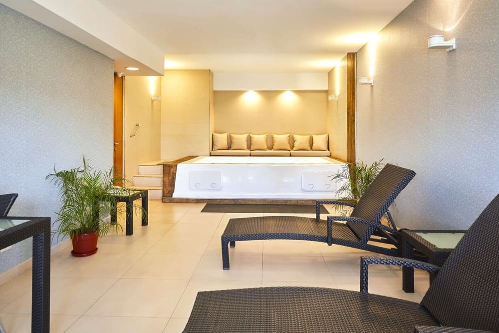 Habitación moderna con cama grande, sector de estar y planta decorativa