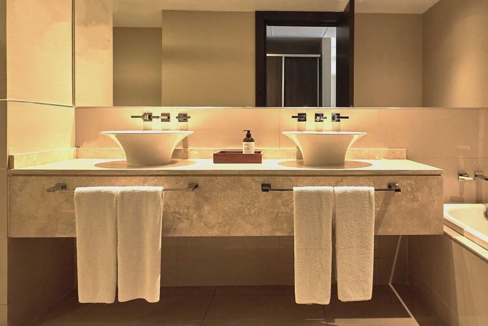 Baño moderno con dos bachas, espejo y toallas