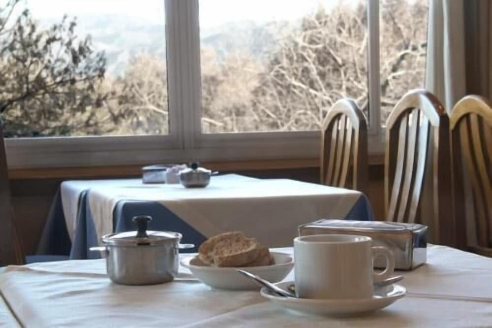 Breakfast table with a white tablecloth, teapot, cup and bread