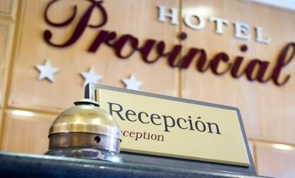 Reception desk with a sign and a wooden wall bearing the hotel name
