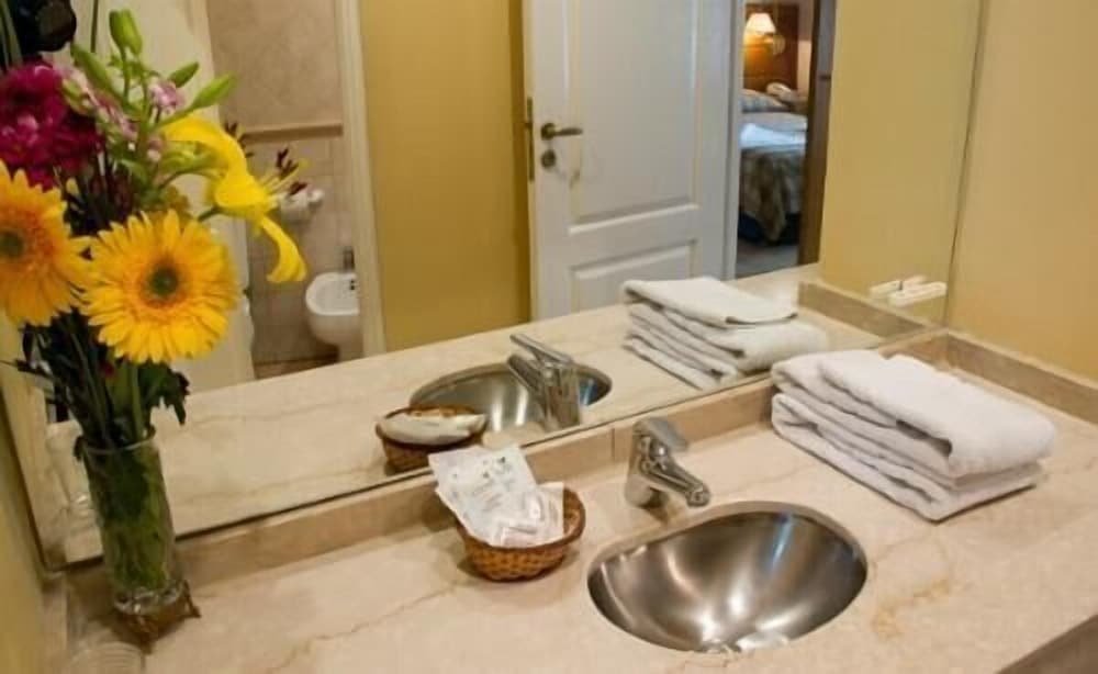 Bathroom with a sink, mirror and a vase of flowers