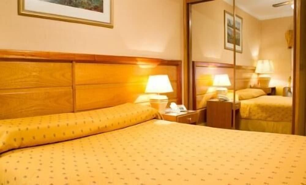 Hotel room with a wooden headboard, patterned duvet and bedside table