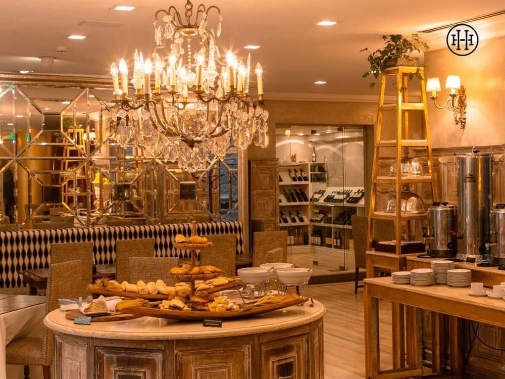 Lobby elegante con una gran araña, sectores de estar y estación de vinos