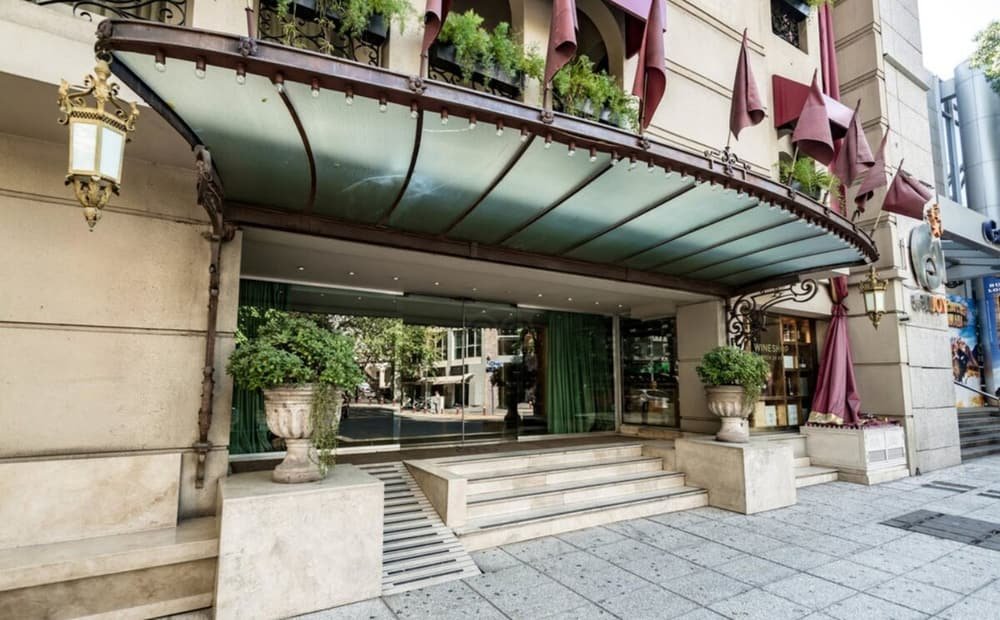 Entrada do hotel com cobertura, degraus e vasos de plantas