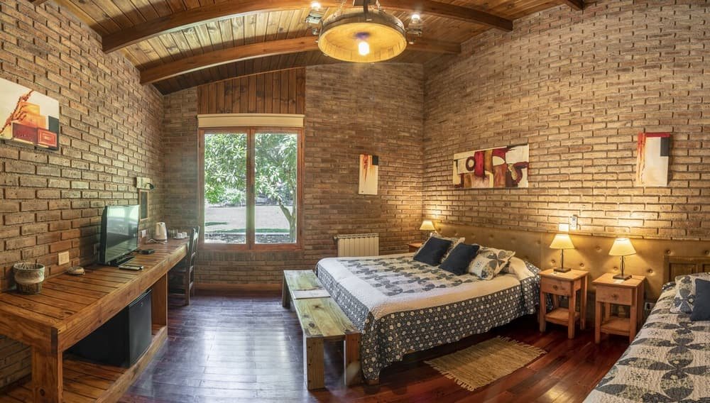 Habitación rústica con ladrillo a la vista, techo de madera y cama grande