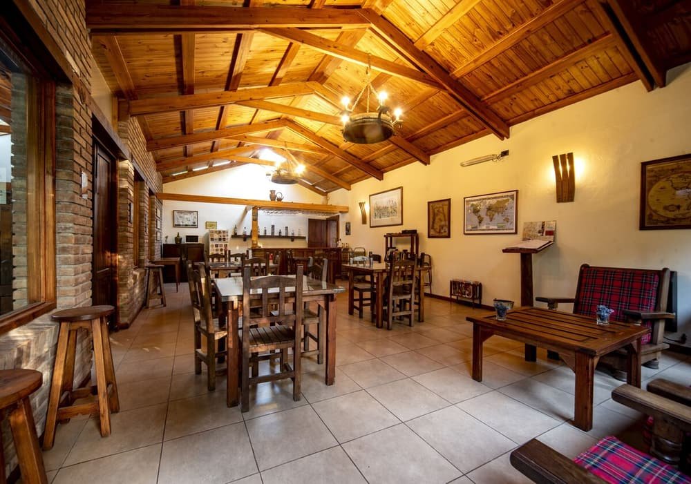 Comedor rústico con mesas y sillas de madera y pared de ladrillo