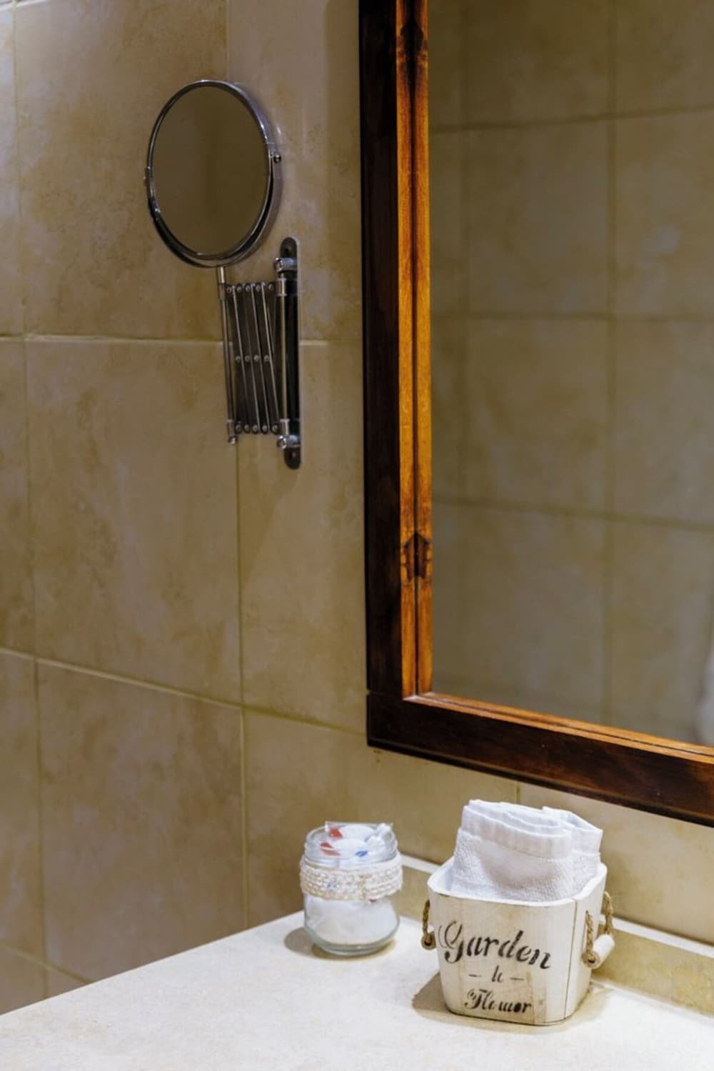 Baño con espejo, toallero y un pequeño frasco sobre la mesada