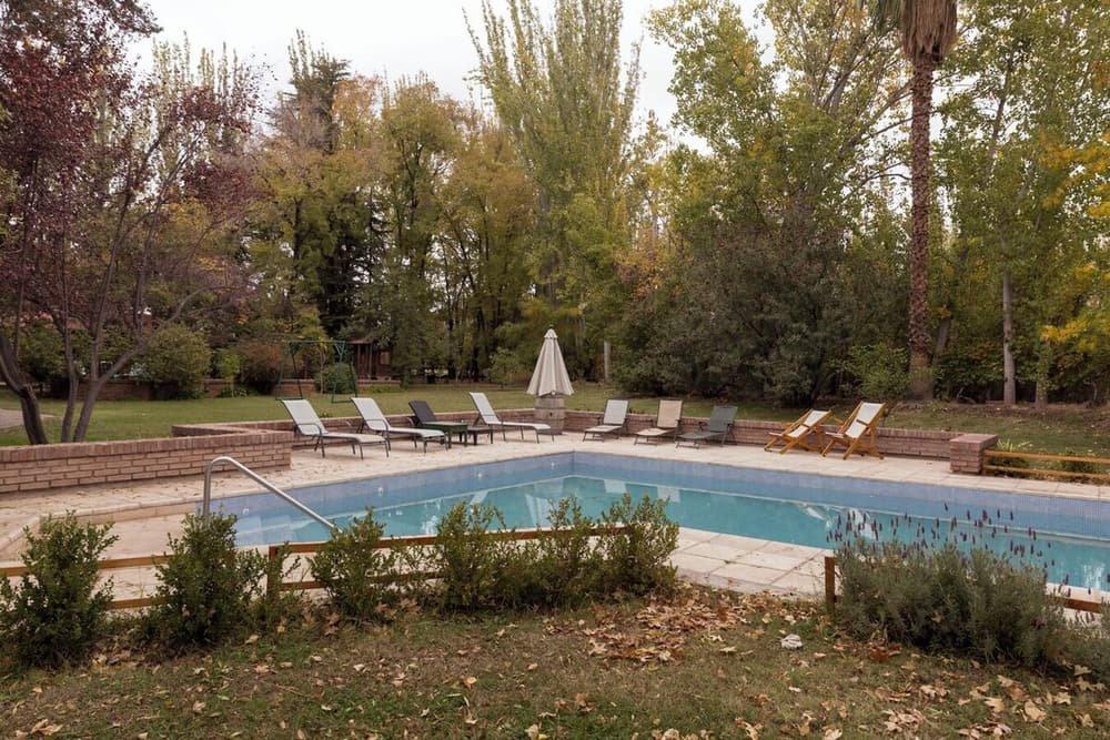 Piscina rectangular con deck, reposeras y una sombrilla