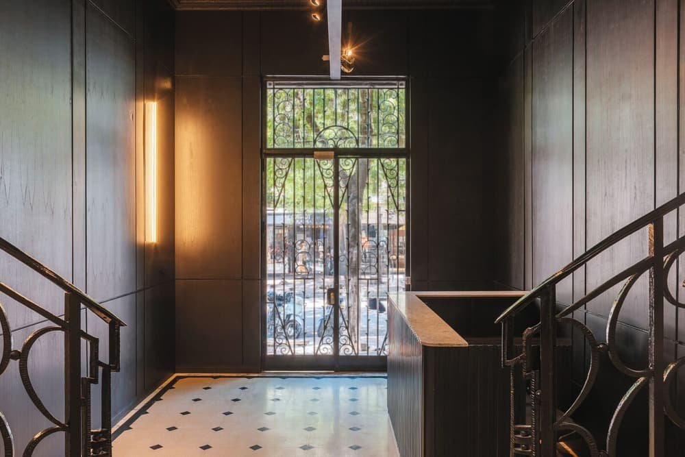 Escalera con baranda metálica y piso con diseño, con vista a un patio exterior