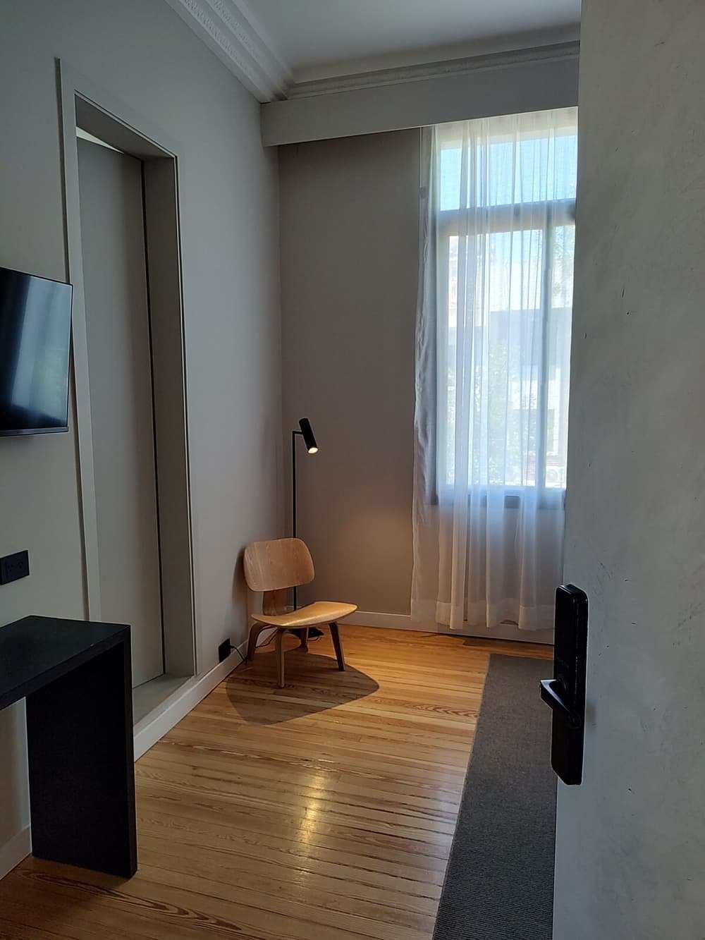 Living moderno con piso de madera, mueble para televisor y ventanal con cortinas