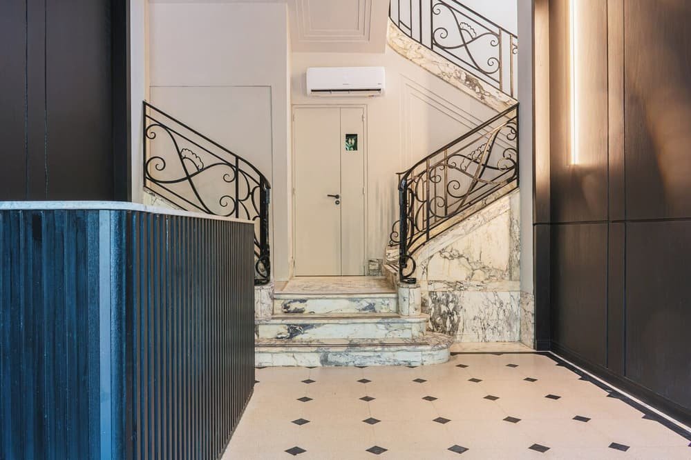 Escalera de mármol con barandas de hierro negro que lleva a una puerta