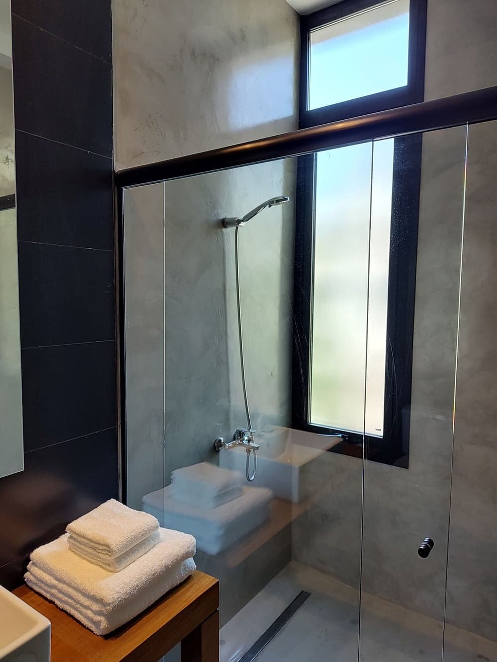 Baño moderno con ducha enmarcada en vidrio, bacha y ventana