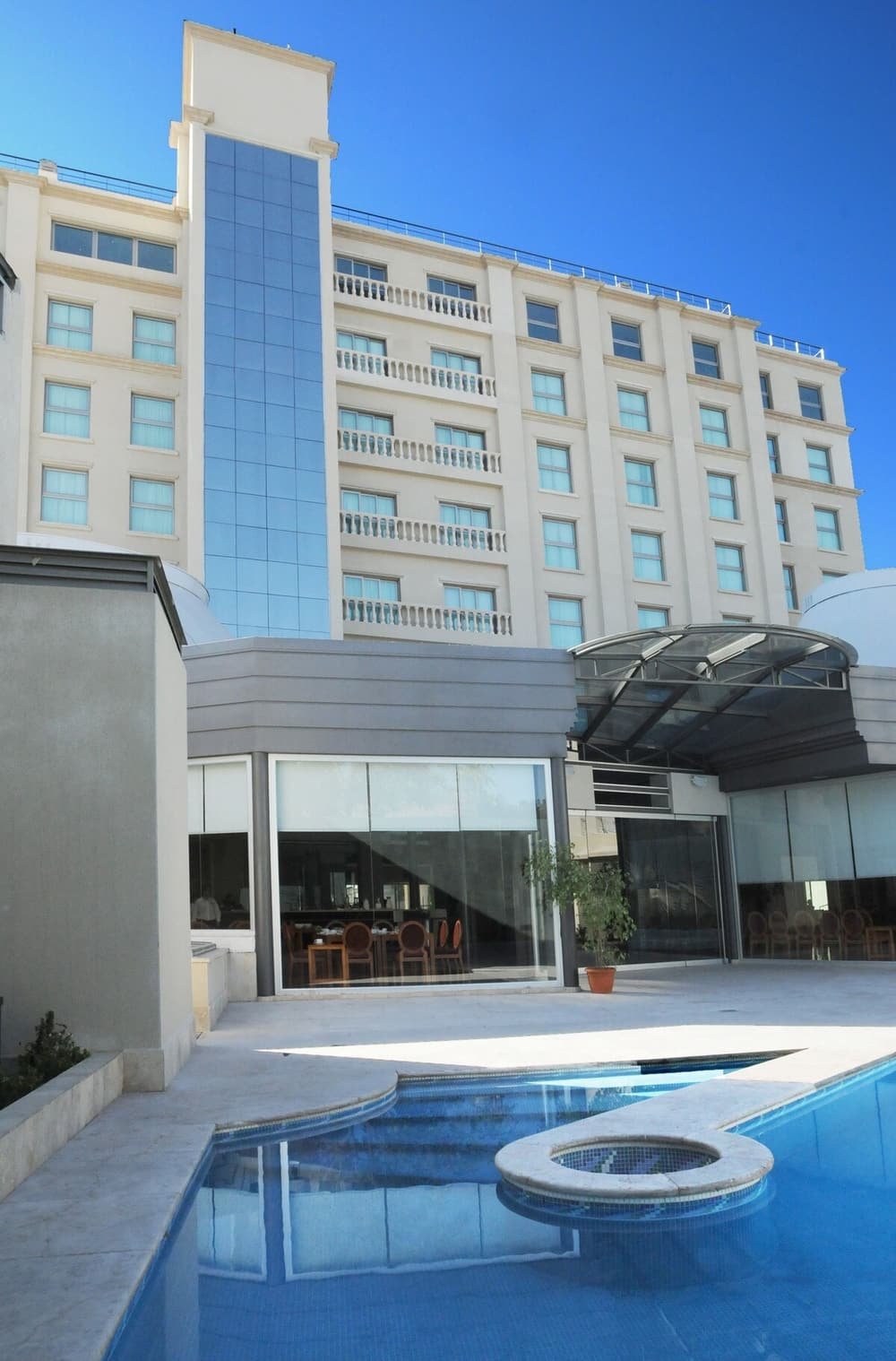 Hotel com piscina, pátio coberto e prédio de vários andares com sacadas