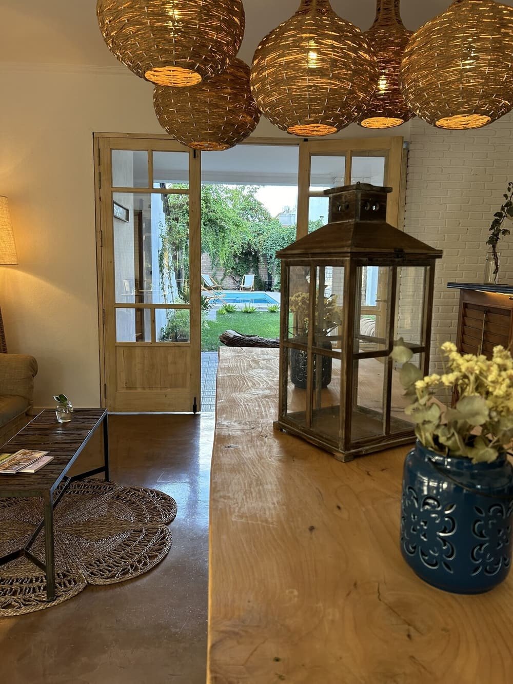 Ambiente con piso de madera, puerta de vidrio hacia la piscina y flores azules