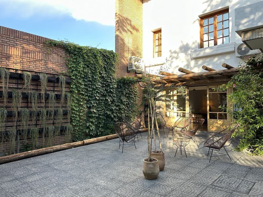 Patio con paredes de ladrillo, pérgola y asientos al aire libre