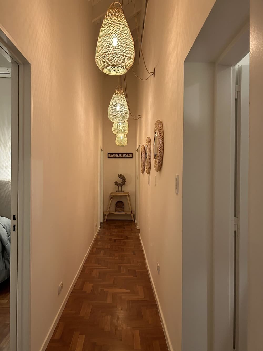 Pasillo con piso de madera, lámpara colgante y un cartel que dice Mendoza