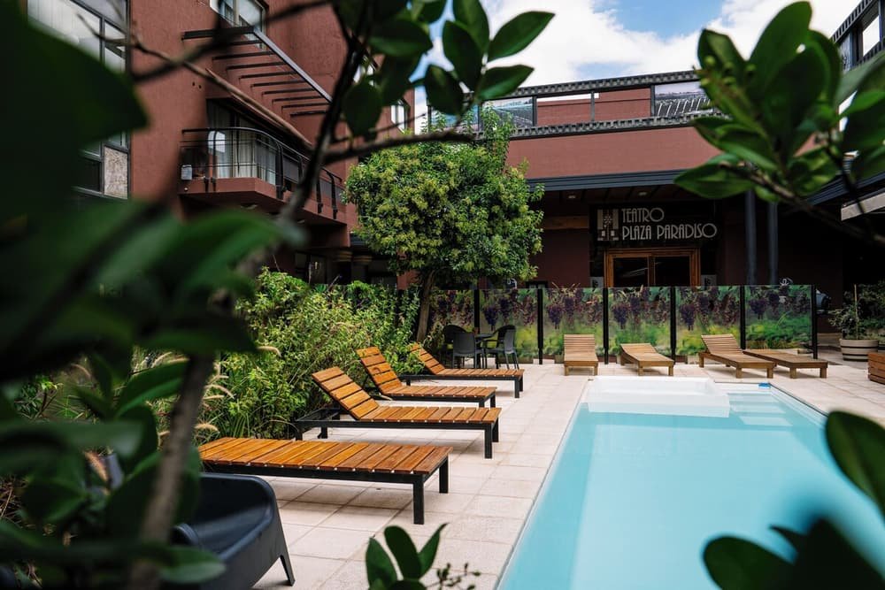 Zona de piscina con reposeras y un edificio con el cartel Teatro Plaza Paradiso