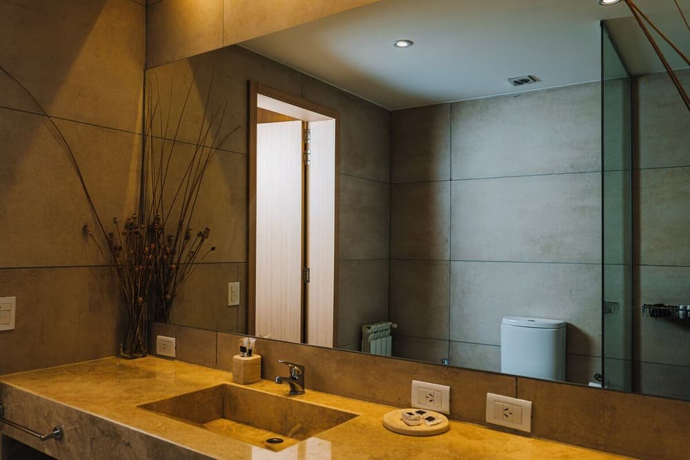 Baño moderno con espejo grande, dos lavabos e inodoro
