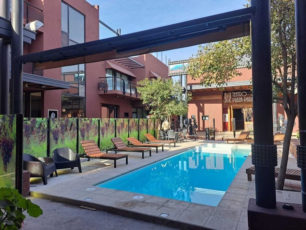 Piscina con reposeras y pérgola, con vista al teatro y la plaza