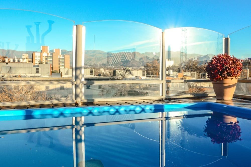Balcón de vidrio con vista a la ciudad, edificios y montañas