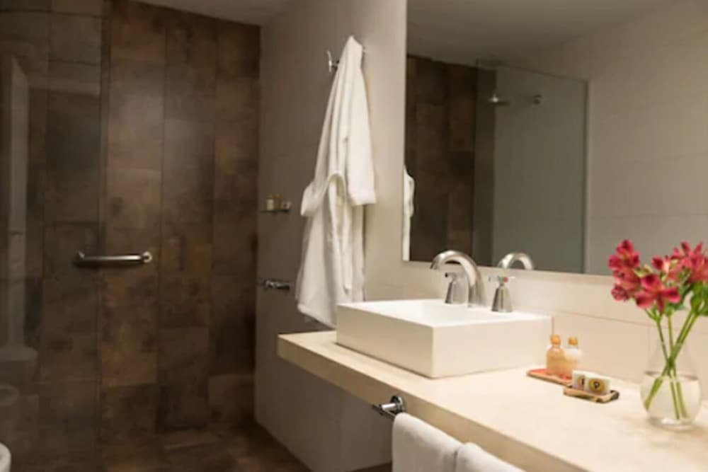 Baño moderno con espejo grande, lavabo blanco y zona de ducha