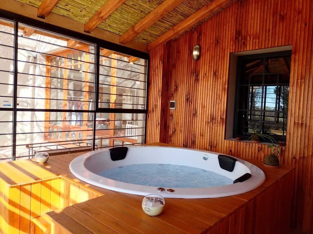 Cabaña de madera con jacuzzi, grandes ventanales y deck de madera