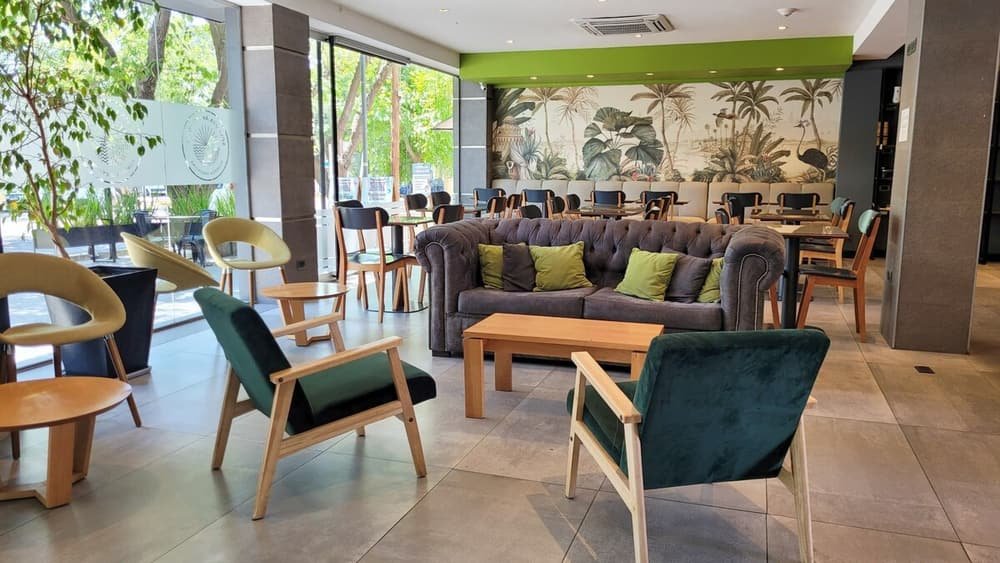 Sector moderno de estar con sillas y sillones, y un mural de plantas tropicales