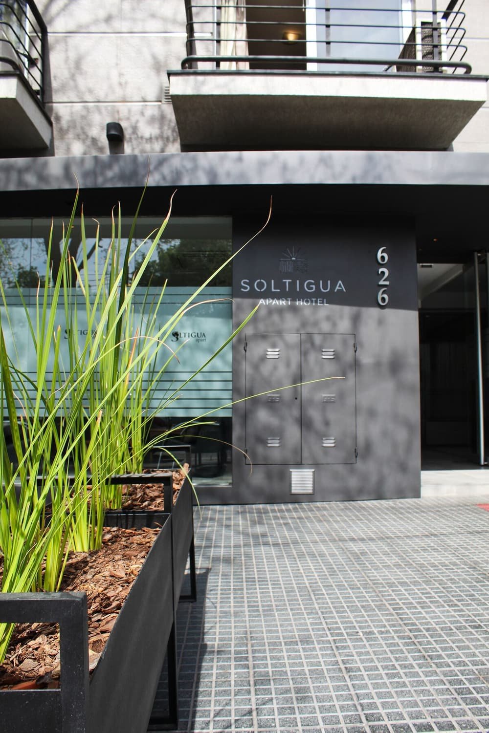 Edificio moderno con cartel Soltigua Apart Hotel y portón con lector de tarjetas