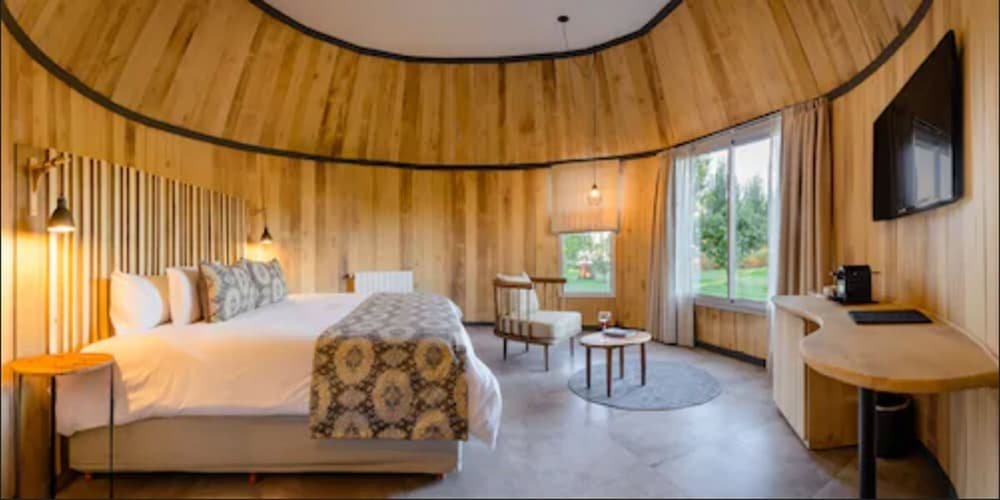Quarto de hotel moderno com cama grande, escrivaninha e televisor