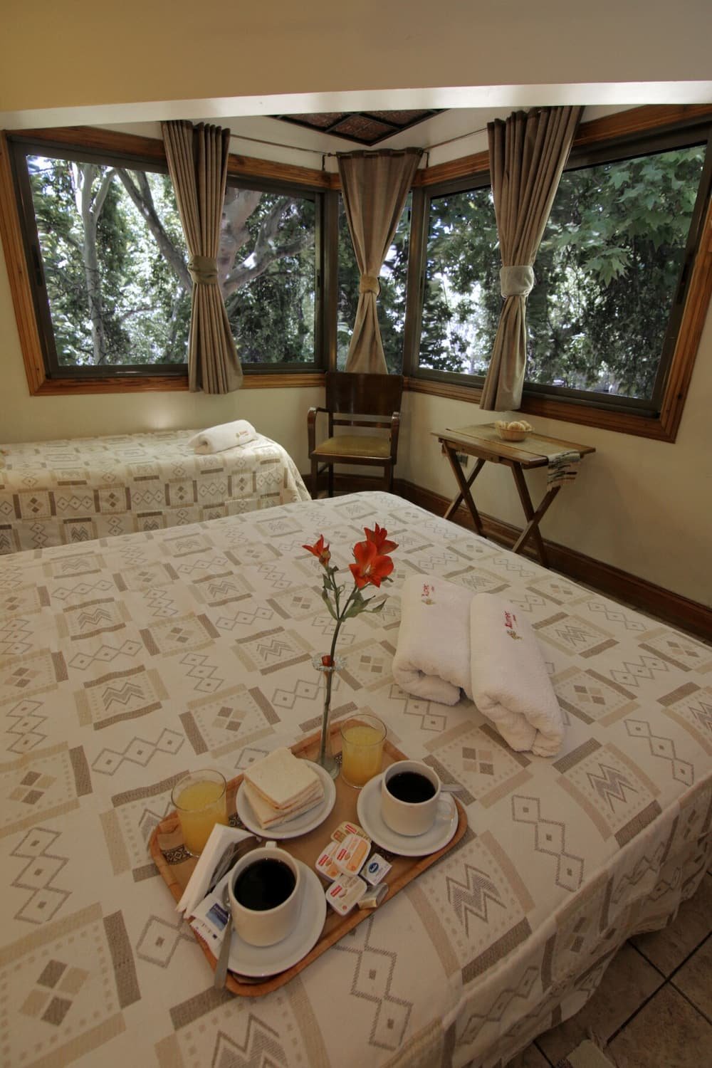 Habitación con cama grande, mesa pequeña con desayuno y ventana con cortinas